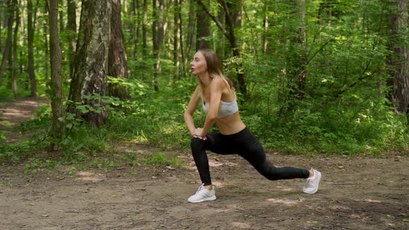 Young Woman Warms Up Before a Fitness Workout in the Park. A Healthy Young Woman Is Warming Up in alt