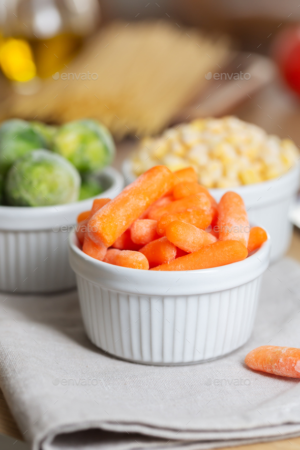 Frozen vegetables such as baby carrot and and Brussels sprouts in the bowls on the kitchen table - Stock Photo - Images