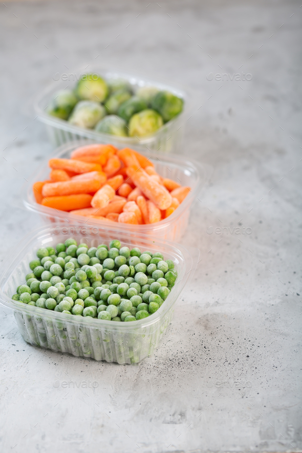 Frozen vegetables such as green peas, brussels sprouts and baby carrot in the storage boxes - Stock Photo - Images