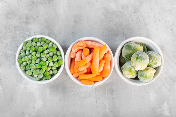 Frozen vegetables such as green peas, brussels sprouts and baby carrot in the white bowls - Stock Photo - Images
