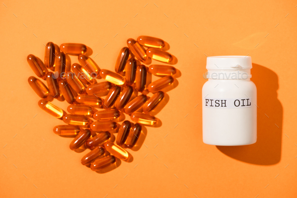 Decorative Heart From Capsules And Container With Fish Oil Lettering on Orange Background