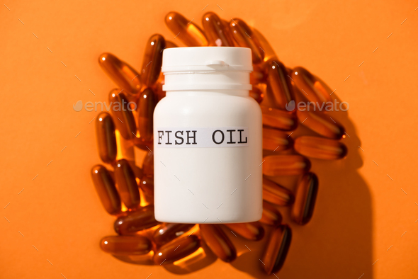 High Angle View of Container With Fish Oil Lettering on Capsules on Orange Background