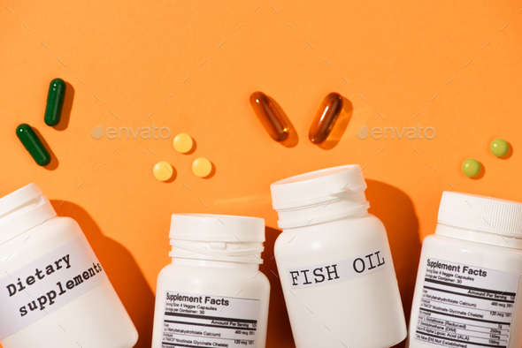 Containers With Fish Oil And Dietary Supplements Lettering Near Pills on Orange Background