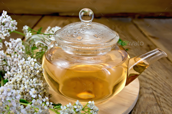 Tea with yarrow in glass teapot on board