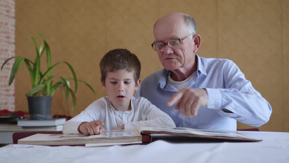Old Elderly Man in Glasses for Vision Together with His Grandson Enjoy Happy Memories Watching a alt