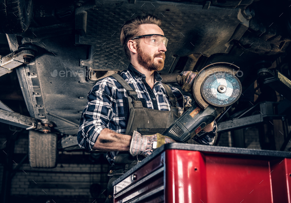 Mechanic in protective googles holds angle grinder. - Stock Photo - Images