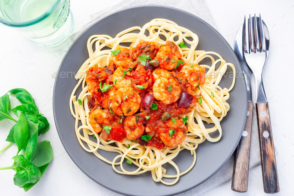Linguine Puttanesca pasta with shrimps in spicy tomato basil sauce horizontal, top view - Stock Photo - Images