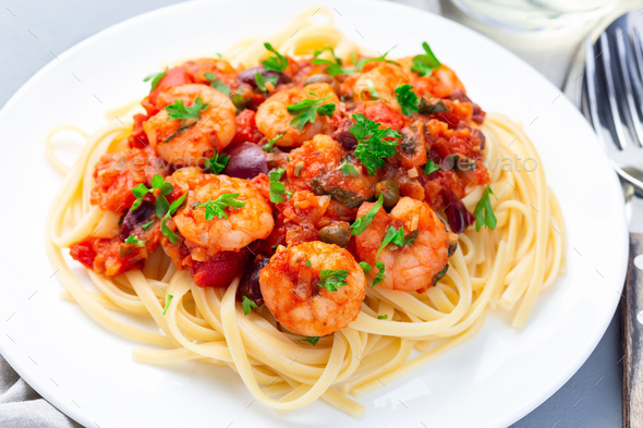 Italian dish shrimp linguine Puttanesca, pasta with shrimps in spicy tomato basil sauce, horizontal - Stock Photo - Images