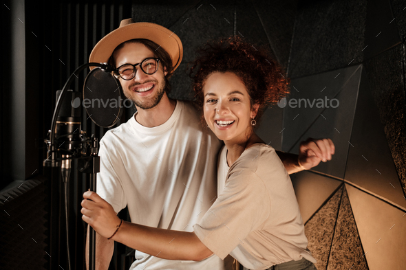 Attractive stylish musicians happily looking in camera working together on new music album in studio - Stock Photo - Images