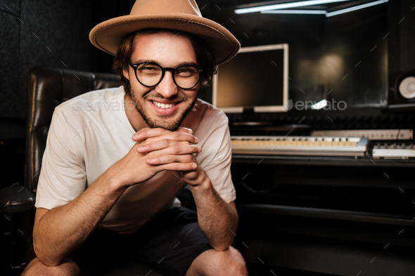 Attractive smiling guy joyfully posing on camera in sound recording studio