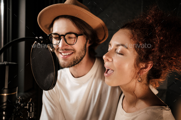 Young musicians sensually singing working together on new music album in sound recording studio