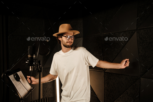 Attractive stylish musician dancing while recording new song in modern sound studio