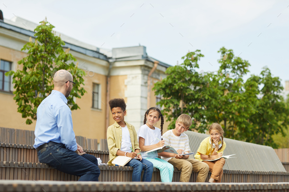 Multi-Ethnic Group of Kids Listening to Teacher Outdoors