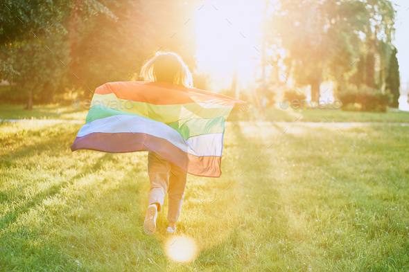 Girl running with rainbow lgbt flag behind back