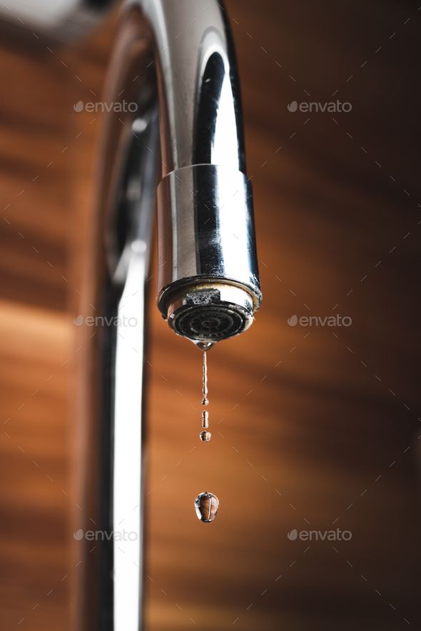 Metal tap and water drop close up. Lime stone in water