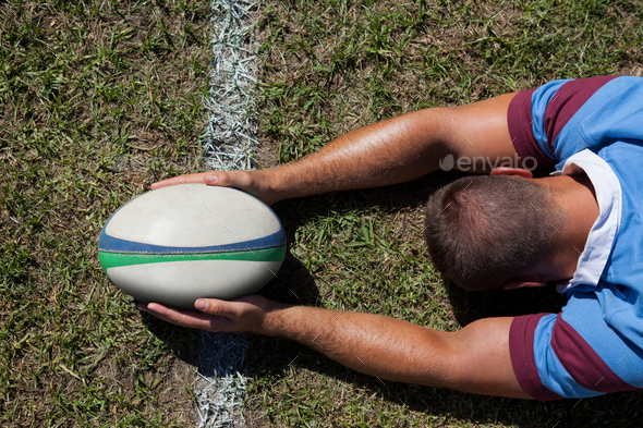 Rear view of rugby player holding ball on goal line