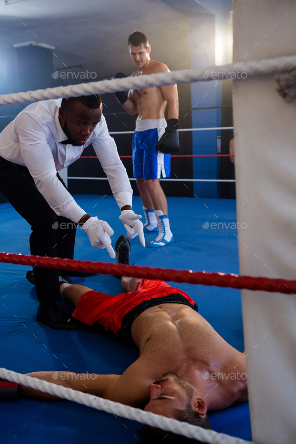 Referee counting by unconscious boxer in ring Stock Photo by Wavebreakmedia