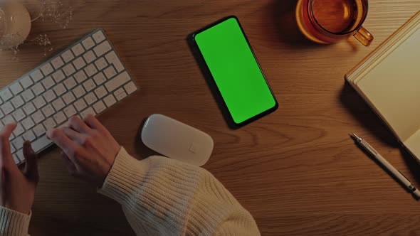 Female Using Green Screen Mobile and Keyboard for Work alt