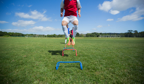 Soccer players practicing on obstacle Stock Photo by Wavebreakmedia