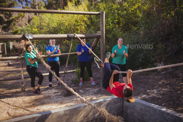 Fit woman climbing a rope during obstacle course training