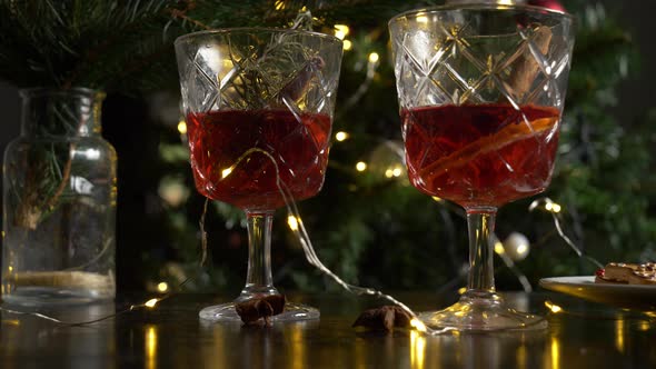 Two glasses with mulled wine near cookies in a table