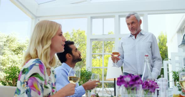 Group of friends interacting with each other while having glasses of wine alt