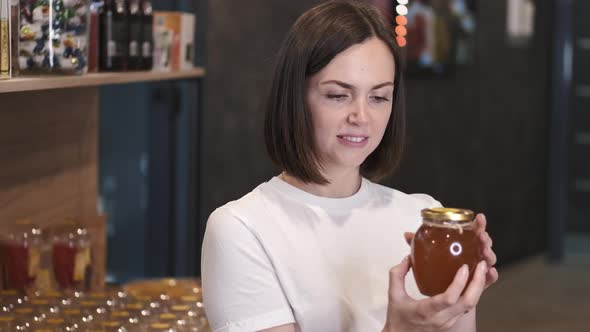 Female Customer Choosing Oney in a Jar at the Store alt