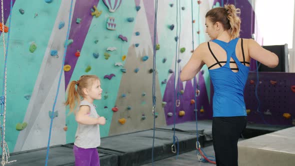 Slow Motion of Mother and Daughter Warming-up Before Climbing Wall in Indoor Gym alt