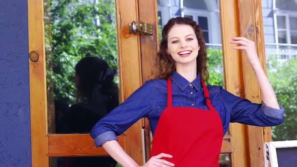 Smiling waitress standing at the entrance of caf������������ alt
