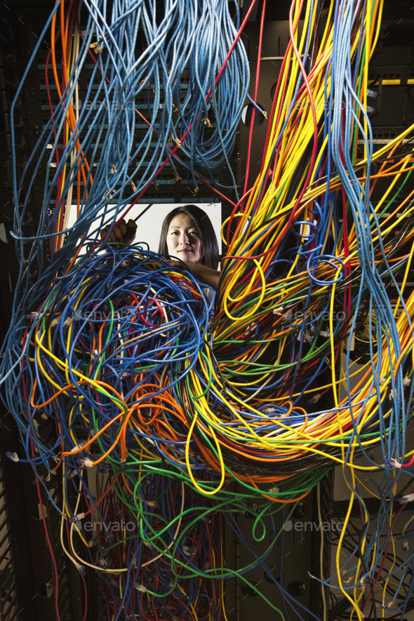 Asian female technician woking on a tangled mess of CAT 5 cables in a server room.