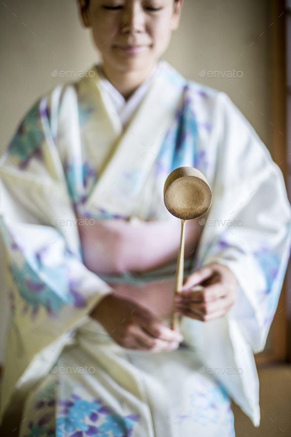 Japanese woman wearing kimono kneeling on floor during tea ceremony