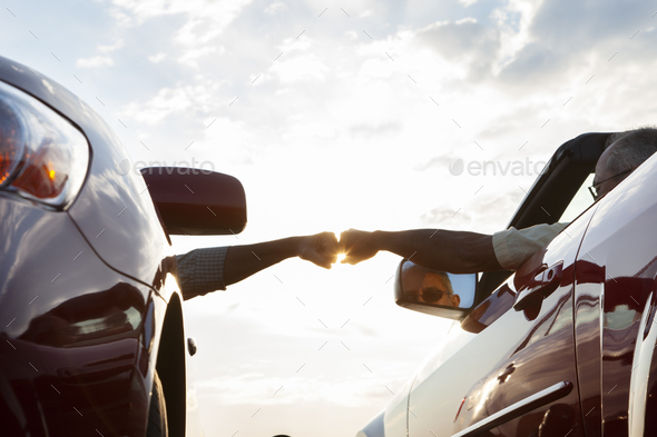 Fist bump between a passenger in one car and driver in another while cars are parked at a rest stop. - Stock Photo - Images