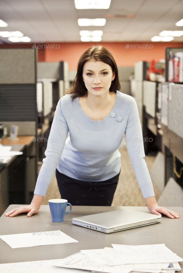 A portrait of a young business woman in her cubicle in a corporate office.