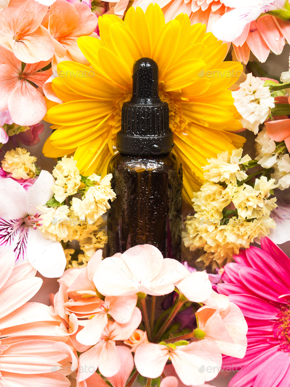 Essential oil in dark bottle with flowers