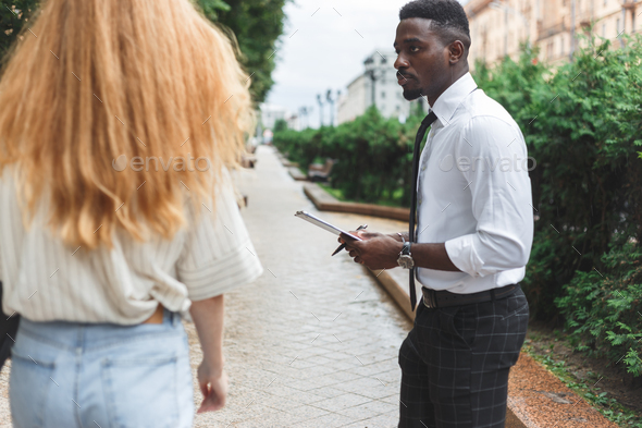 Obsessive black man in business attire interview on the street bothering passersby with questions