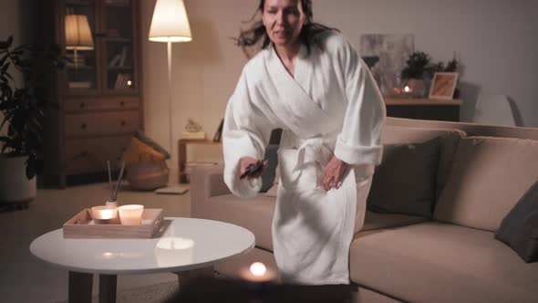 Woman In Bathrobe Watching TV In Evening alt