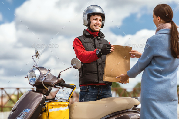 Courier Giving Package To Girl Delivering Food On Scooter Outside Stock  Photo by Prostock-studio