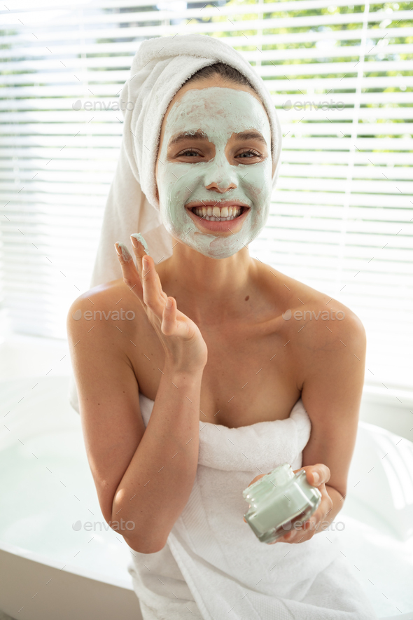 Portrait of woman applying face pack in bathroom