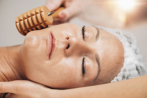 Maderotherapy Face Massage with Wooden Roller. Reducing Cheeks Stock Photo by microgen