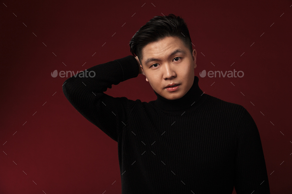 Image of confused asian man posing and looking at camera
