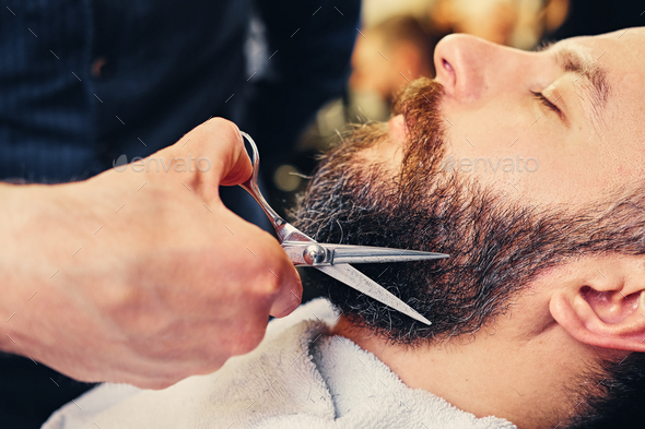Close-up image of barber makes beard cut of a man.
