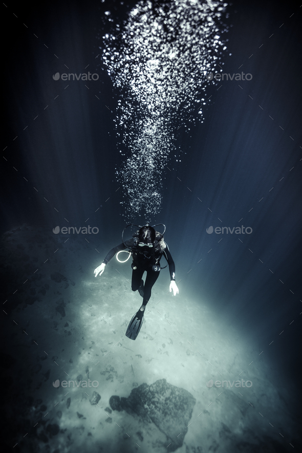 High angle underwater view of diver wearing wet suit and flippers, air bubbles rising. - Stock Photo - Images