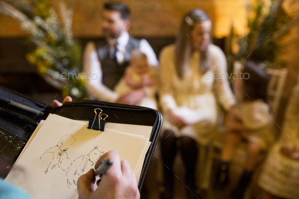 Over the shoulder view of artist sketching family during naming ceremony in an historic barn. - Stock Photo - Images