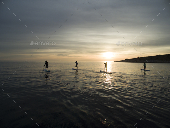 High angle shot of people on paddleboards at sunset.