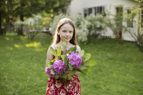 A young girl holding a bunch of purple hydrangea flowerheads.