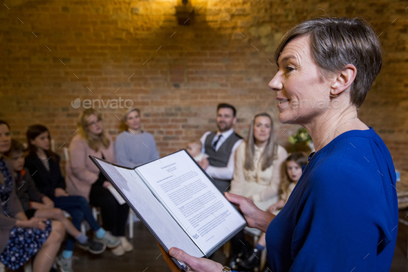 Celebrant performing naming ceremony for parents and their baby daughter in an historic barn. - Stock Photo - Images