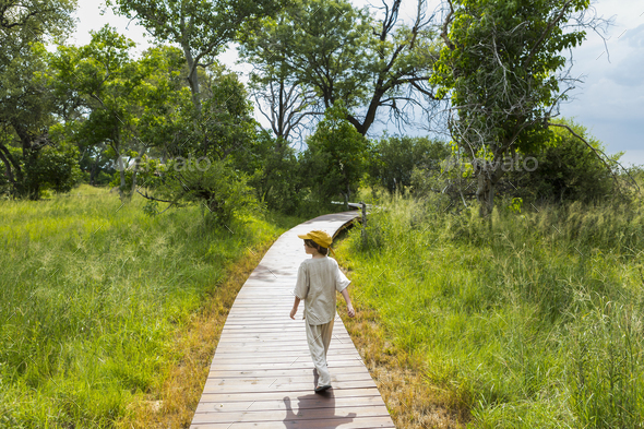 6 year old boy walking on wooden walkway in a safari camp.