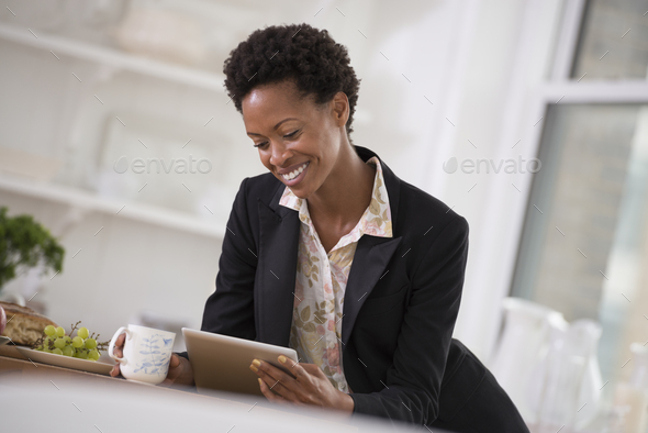 A business environment, a light airy city office. Business people. A woman in a black jacket using a digital tablet.