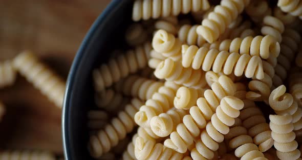 Bowl with Dry Pasta Fusilli Rotates Slowly alt