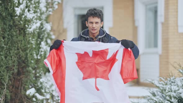 Portrait of Cheerful Handsome Middle Eastern Teen Boy Holding Canadian Flag Talking and Gesturing in alt